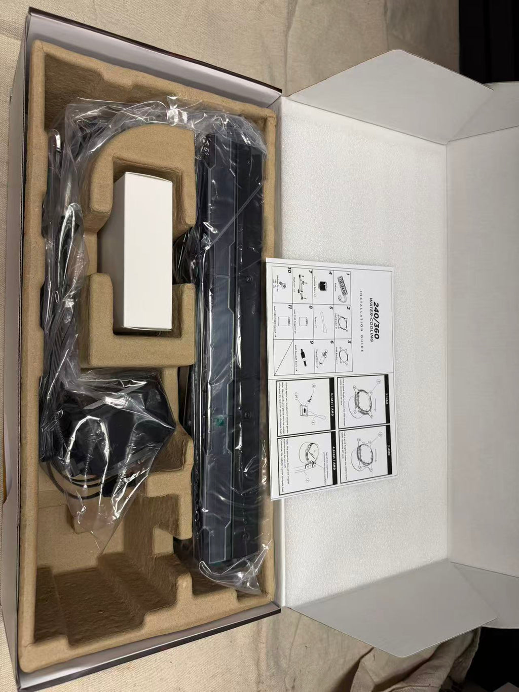 Open HotBell HB3XCF1 black liquid CPU cooler package with radiator, pump unit, cables, packaging inserts, and instruction guide